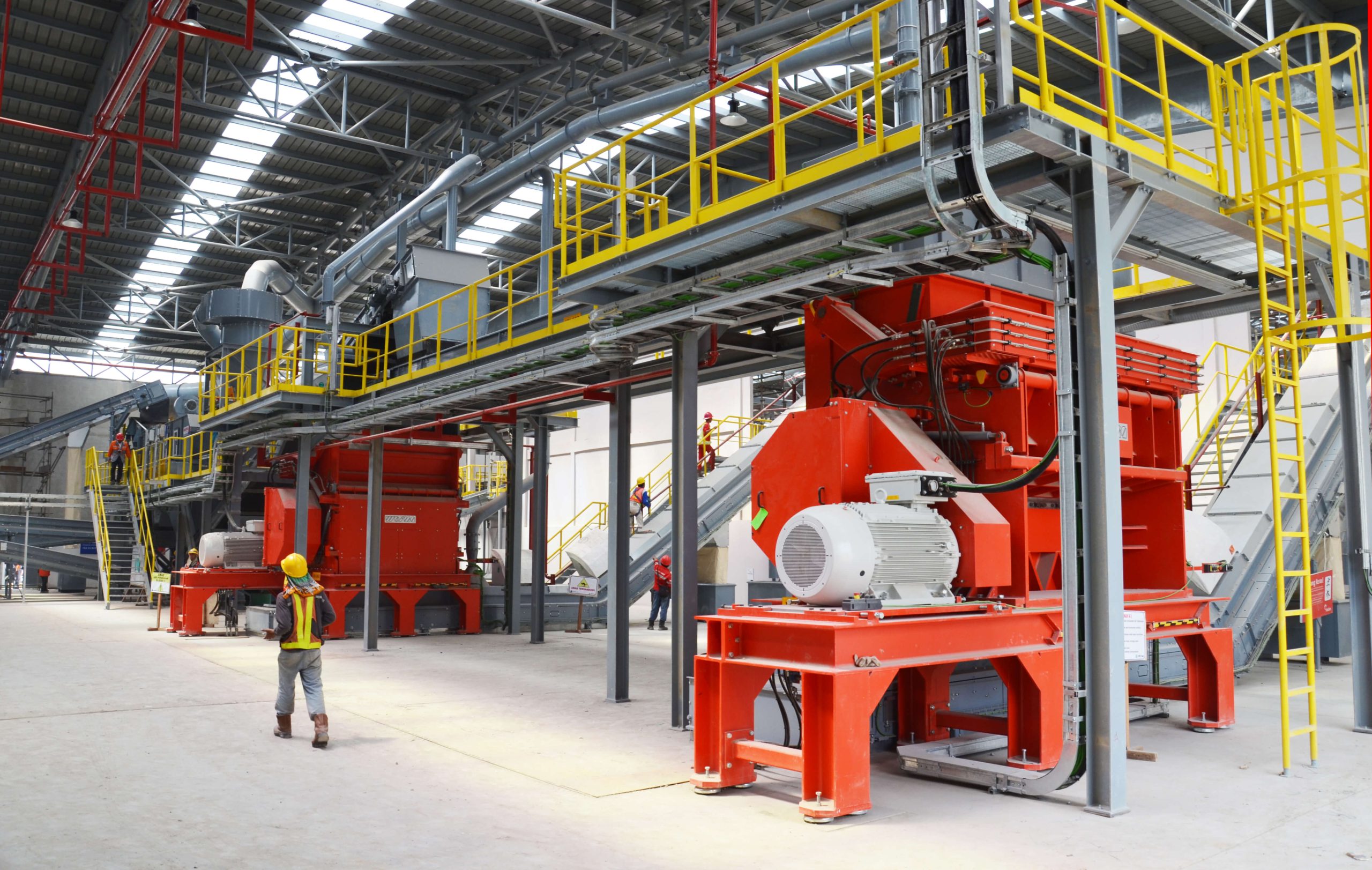 Two WEIMA FineCut 2500 shredders at Geocycle with belt drive in a hall with one person in front of them