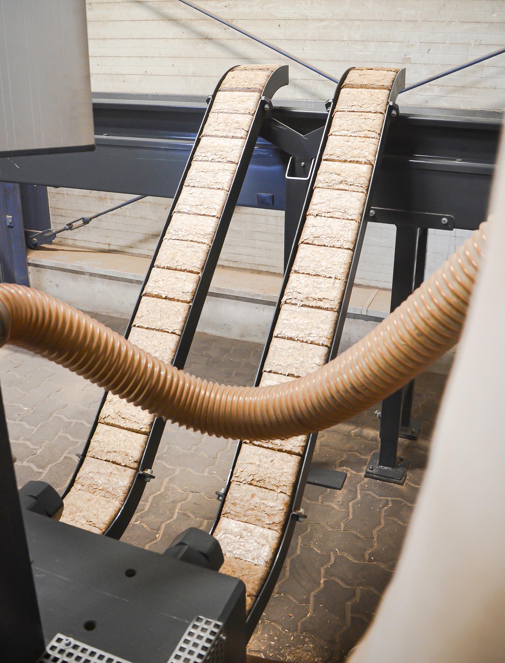 Rectangular briquettes from wood chips are discharged from the press