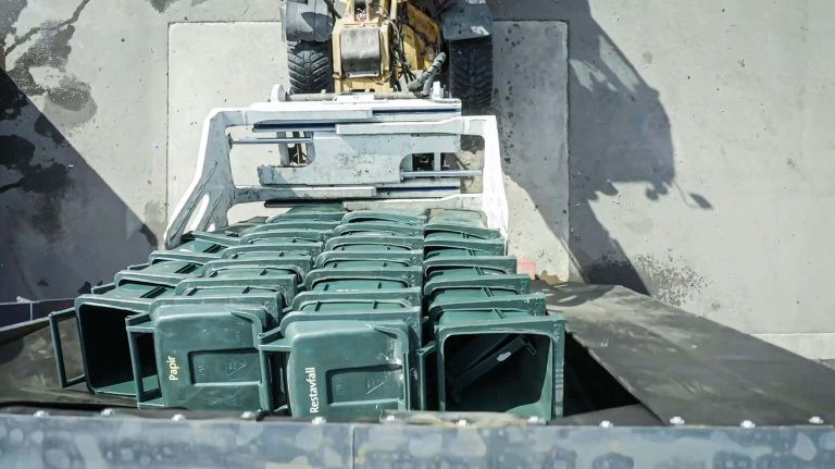 The garbage cans are fed into the shredder through the lamella curtain of the Doghouse hopper attachment.