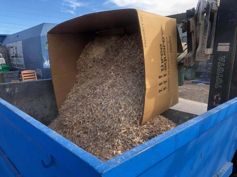 shredded wood is placed in a dumpster for recycling