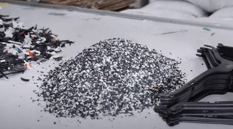 shredded and granulated clothes hangers next to recycled new hangers on a table