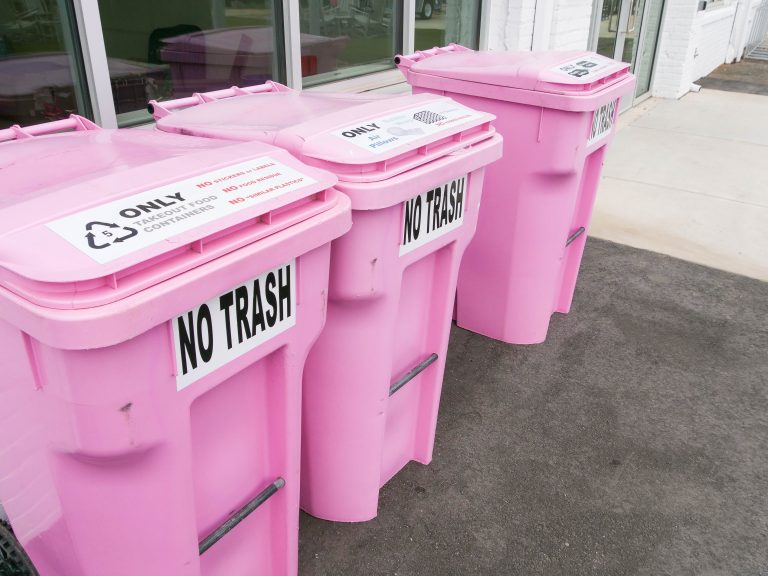 pink recycling bins sit outside a building with a "NO TRASH" sign on them