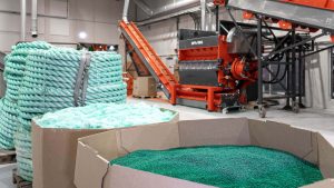 Shredder für Kunststoffe von WEIMA mit zerkleinerten Seilen, Netzen und Tauen, davor Regranulat