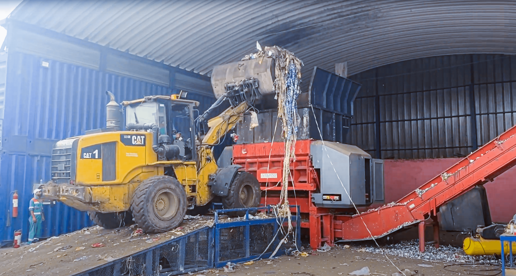 WEIMA Shredder für Abfall bei Polluclean befüllt von einem gelben Radlader