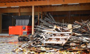 WEIMA Shredder neben Haufen aus Altholz