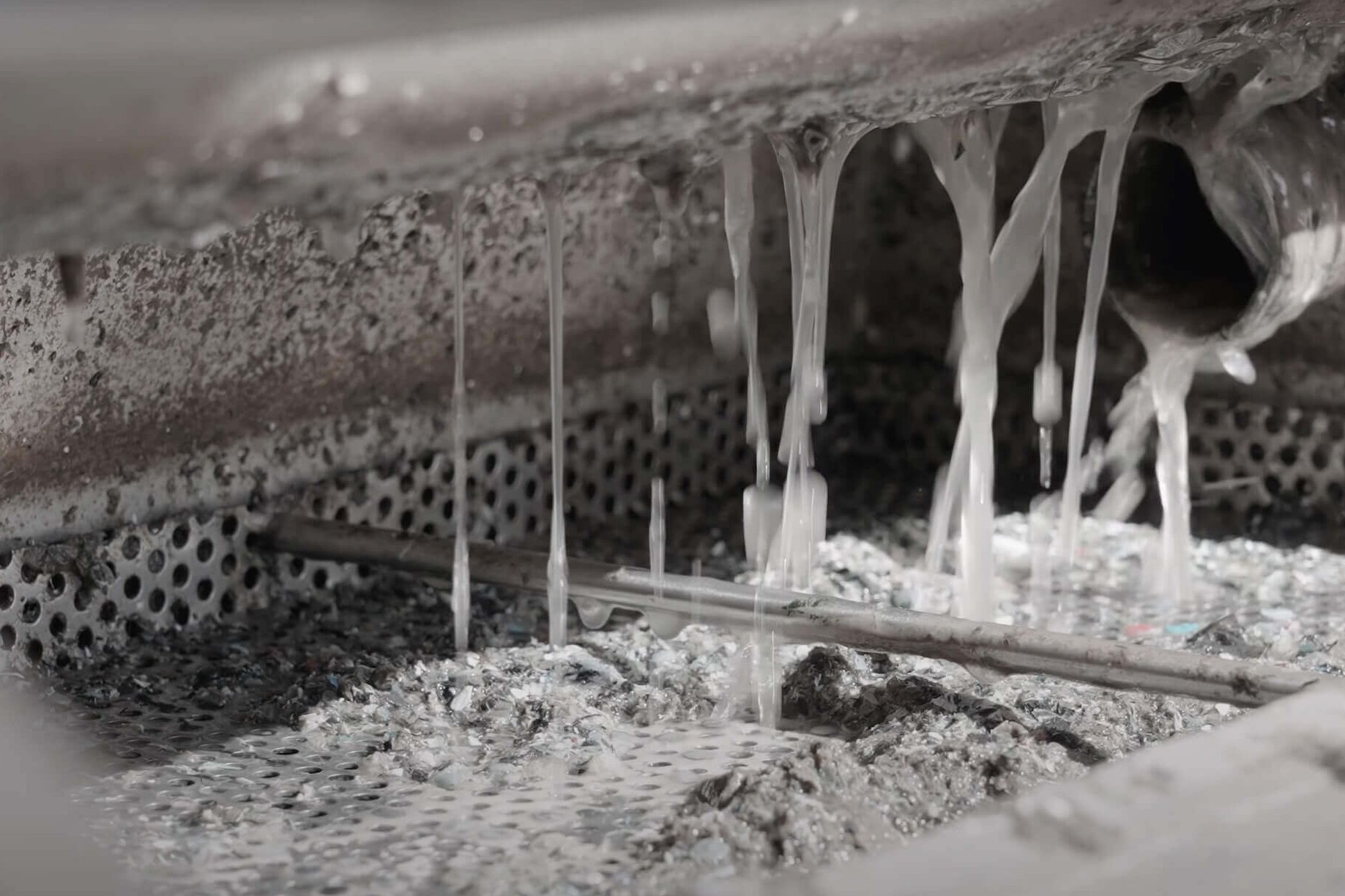 Klare Flüssigkeit tropft in eine Auffangwanne aus Metall