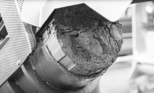 dried and compressed grinding sludge on discharge pipe of a puehler press