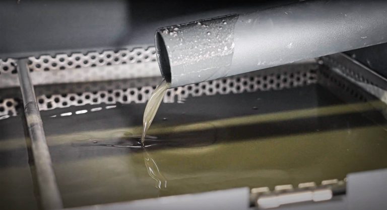 Squeezed coolant from grinding sludge flows out of a pipe into a catch basin