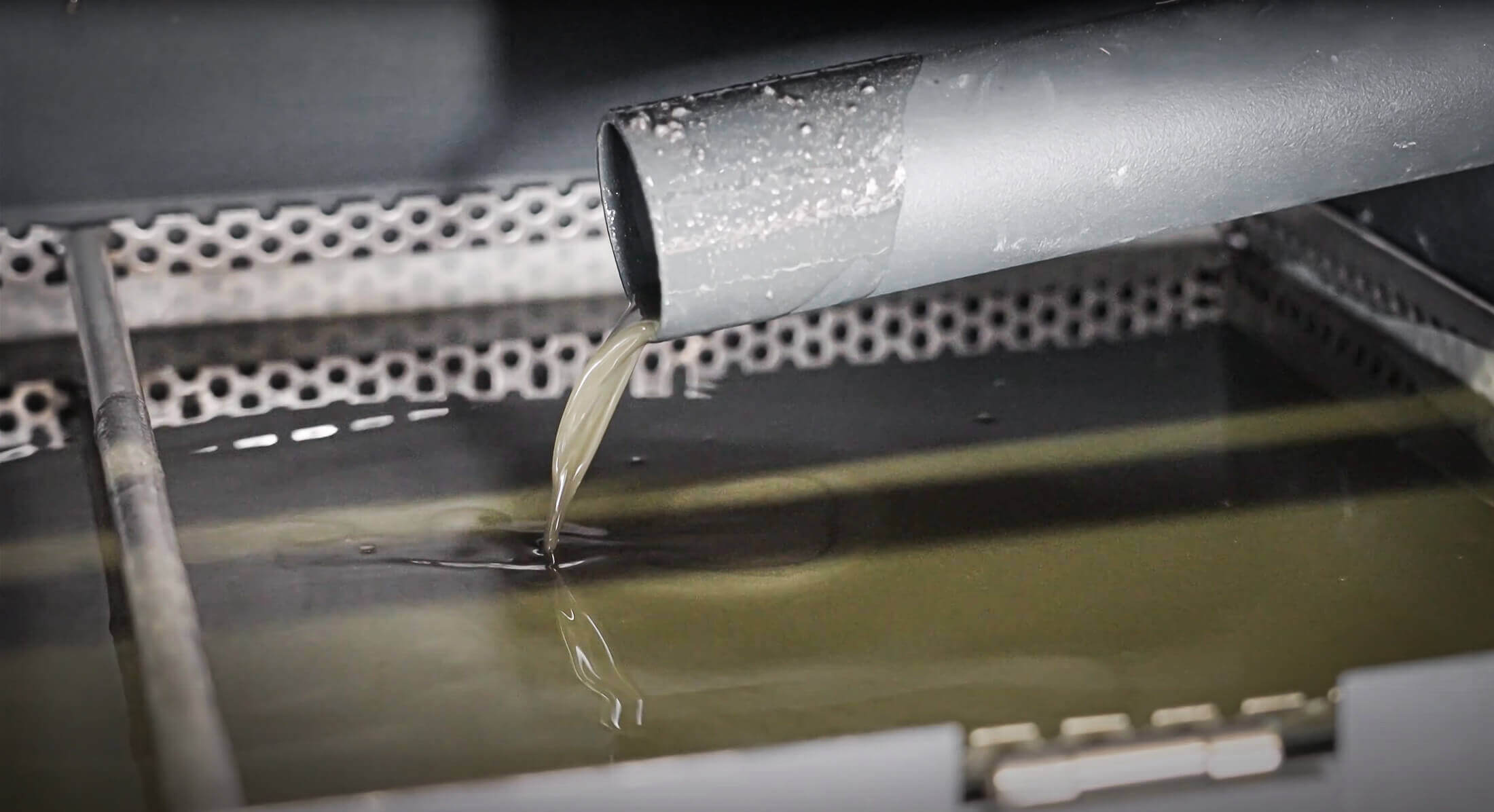 Squeezed coolant from grinding sludge flows out of a pipe into a catch basin
