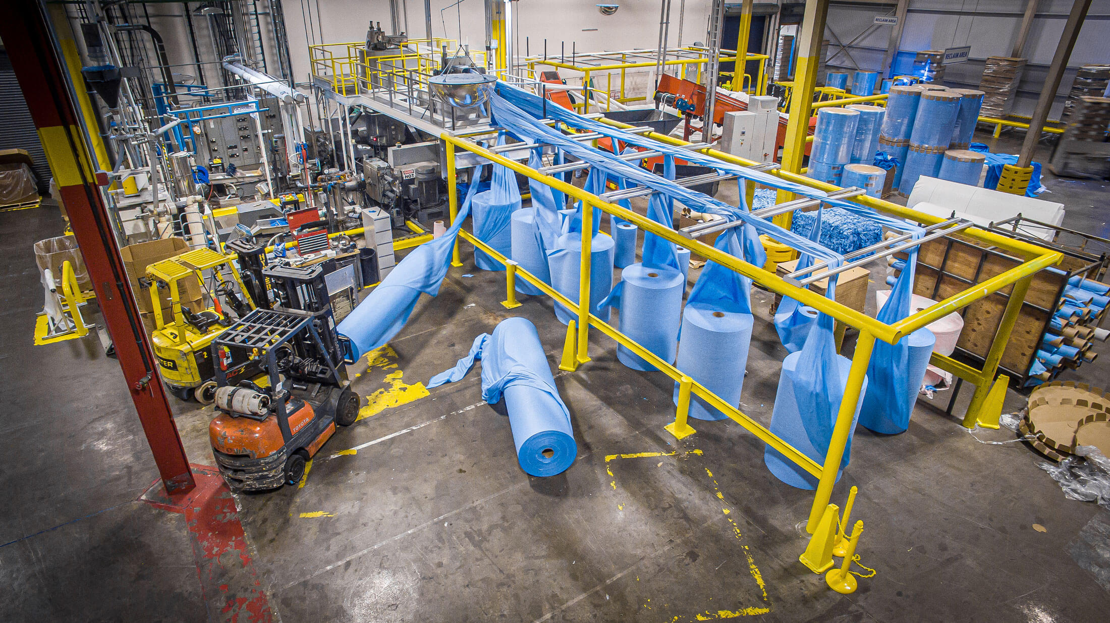 blue textiles bales in a row next to shredding and recycling machines inside a production hall