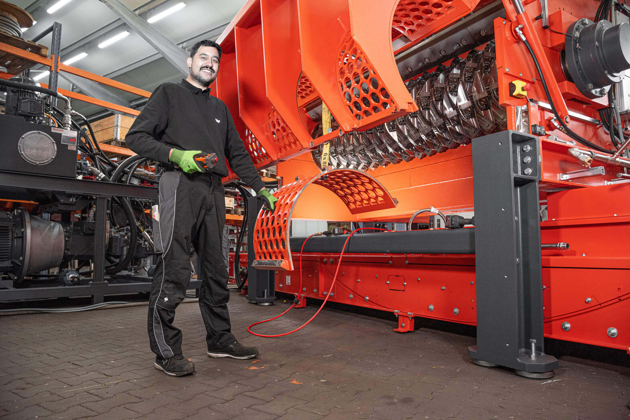 Mechaniker mit WEIMA Kleidung vor einem orangen Shredder
