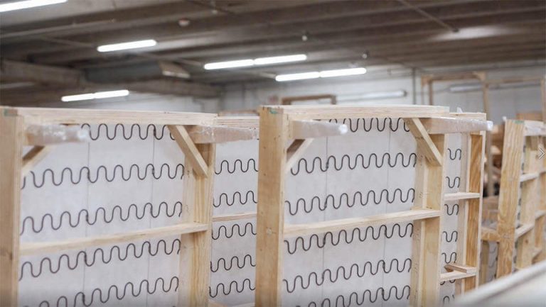Unfinished wood beds stand on their sides in a warehouse.