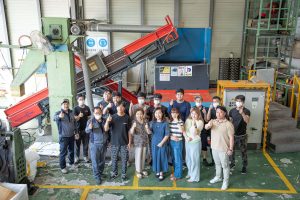 Eine Gruppe koreanischer Mitarbeitender stehen vor einem WEIMA Shredder