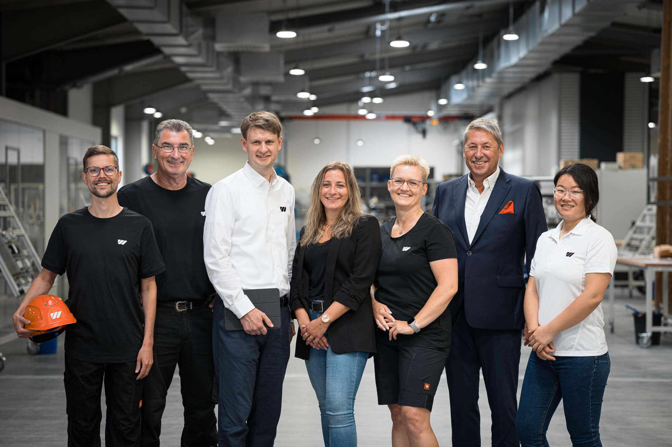 Sieben WEIMA Mitarbeitende stehen nebeneinander und schauen in die Kamera