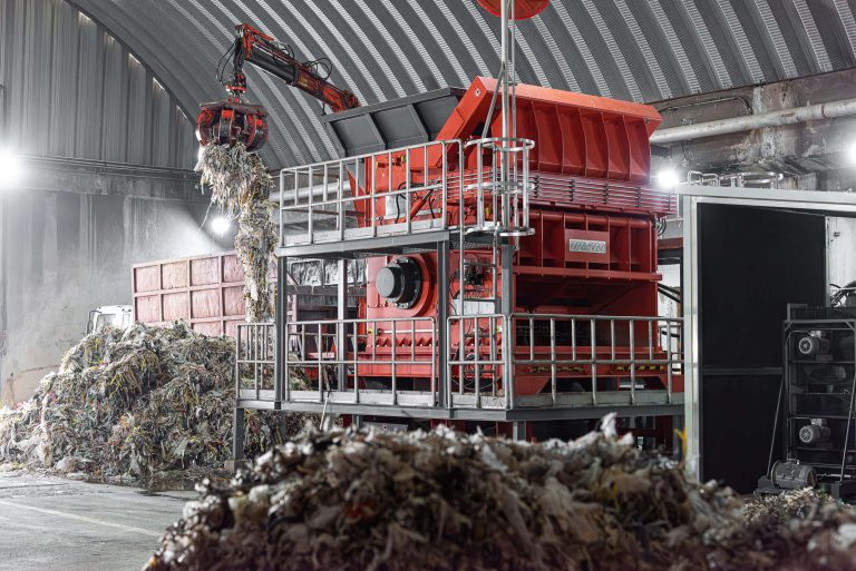 WEIMA PreCut 2500 shreds pulper waste from paper recycling, loaded via crane