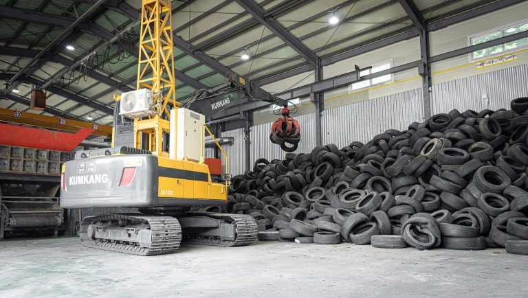 Yellow crane next to a pile of used tires