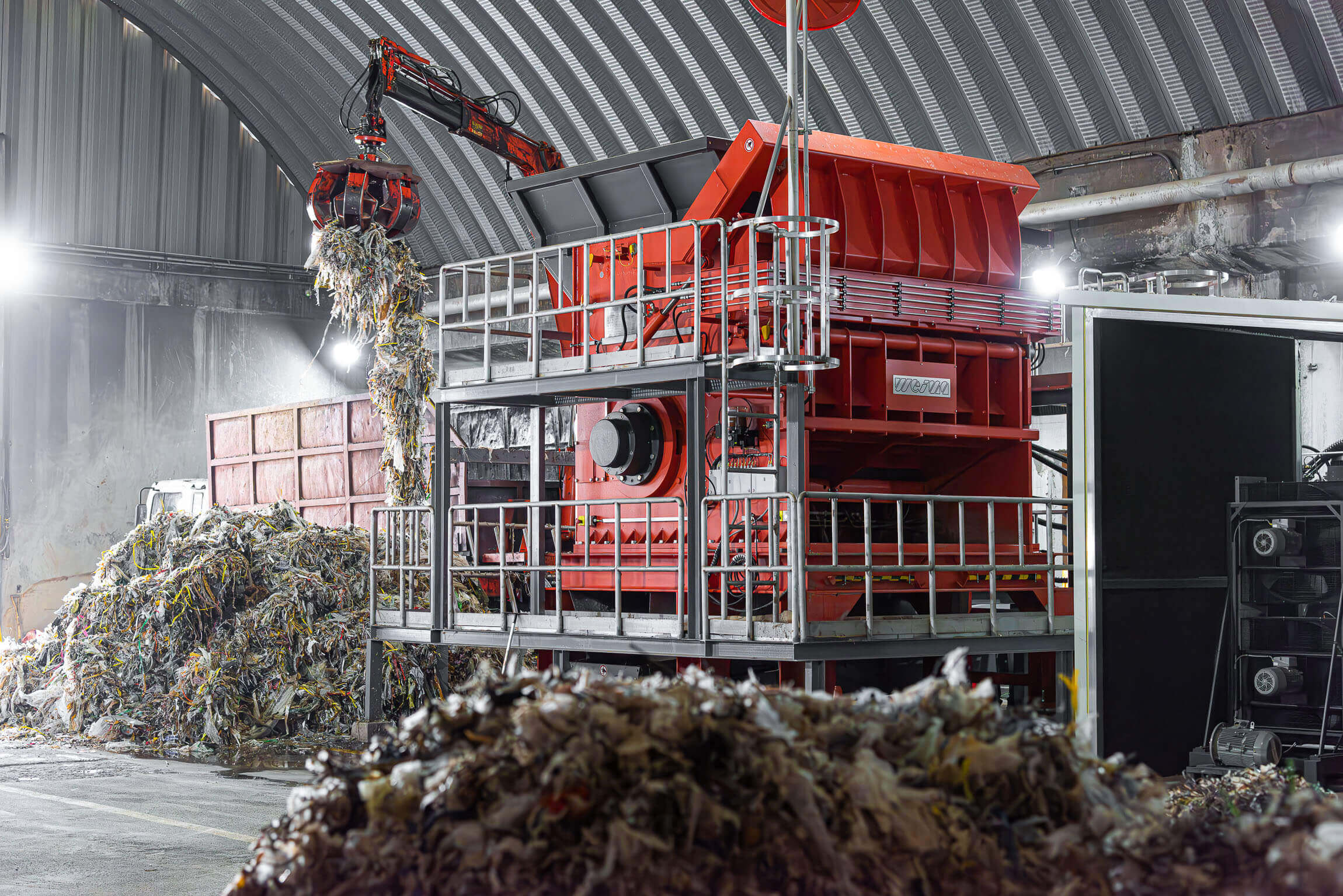 An orange WEIMA shredder is loaded with pulper ropes from paper recycling
