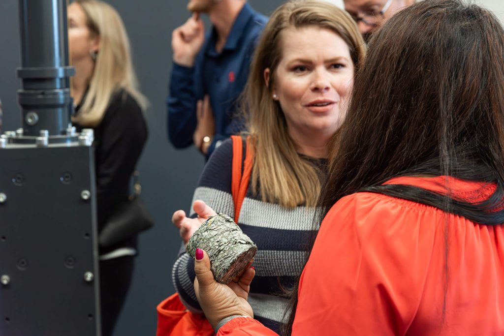 Two attendees have a discussion, while one holds a briquette made of money.