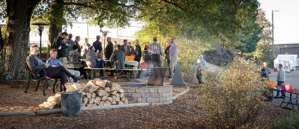 A group of people gather to network around a fire pit.