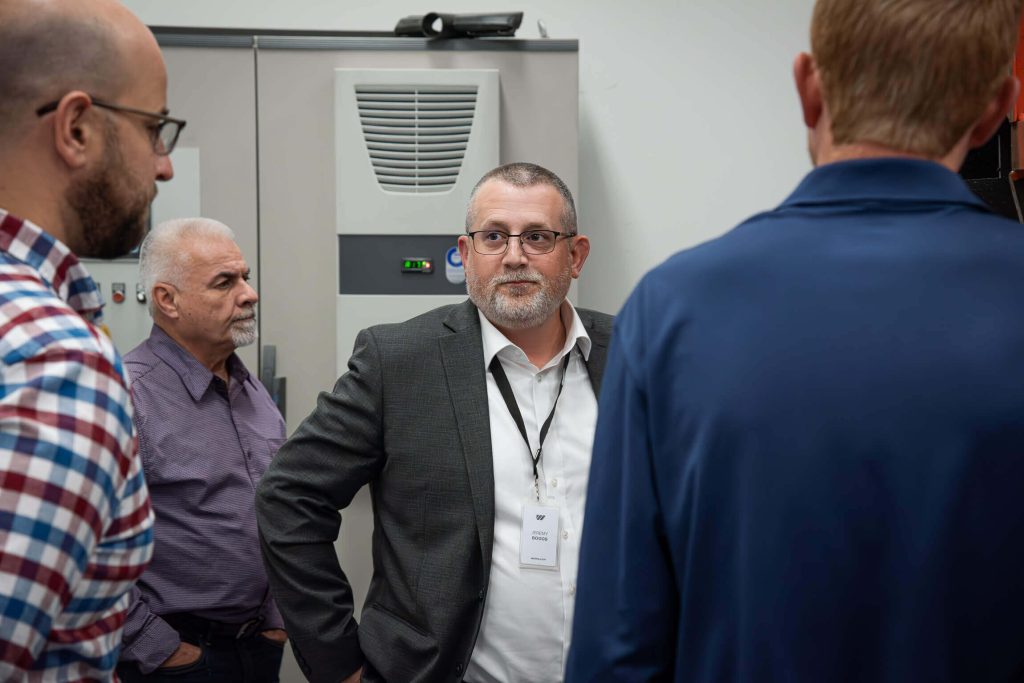 National Sales Manager, Jeremy Boggs, fields questions beside a control panel.