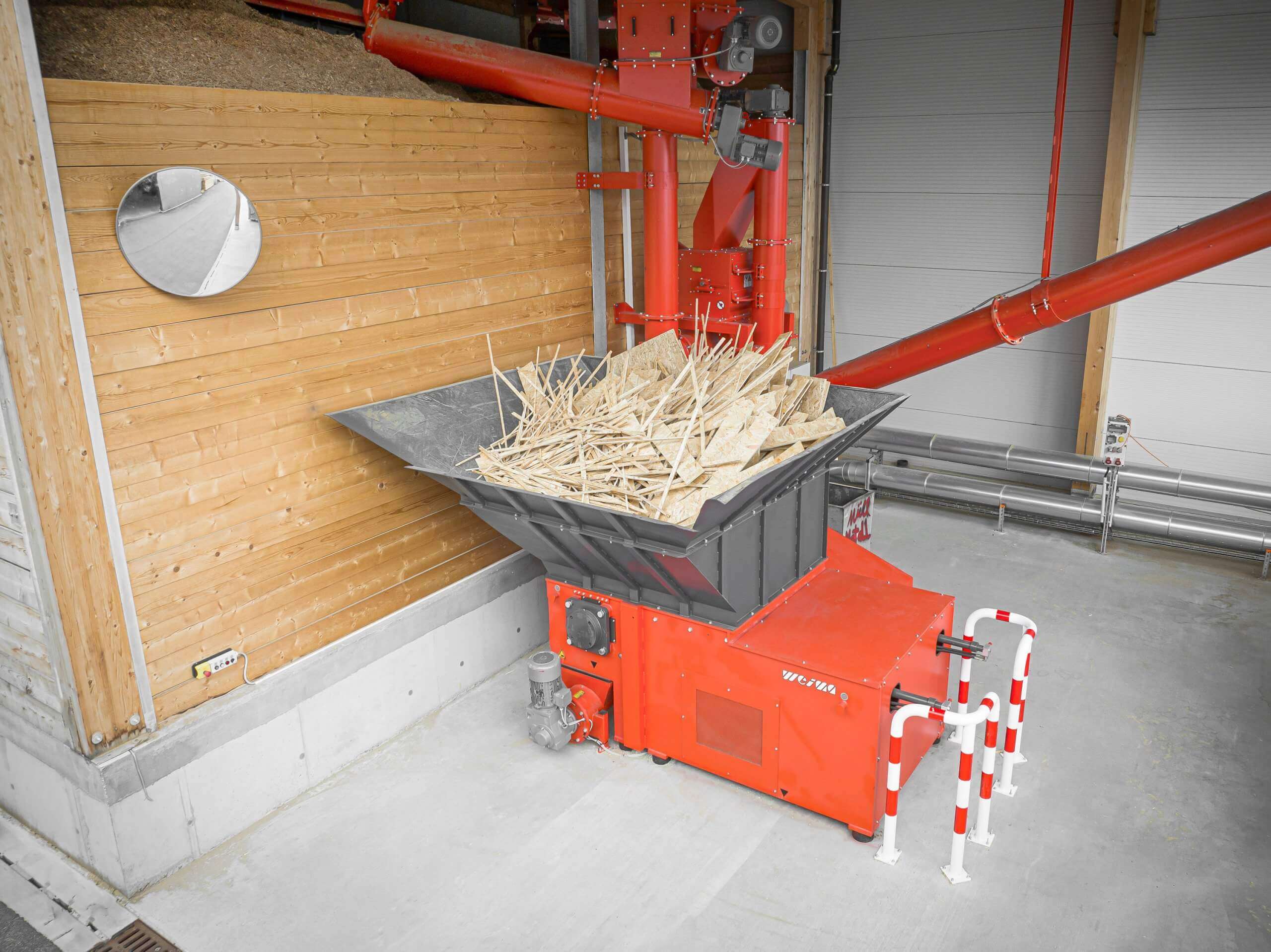Mit Holzabfällen befüllter WEIMA WLK 1500 Shredder neben einem Spänebunker