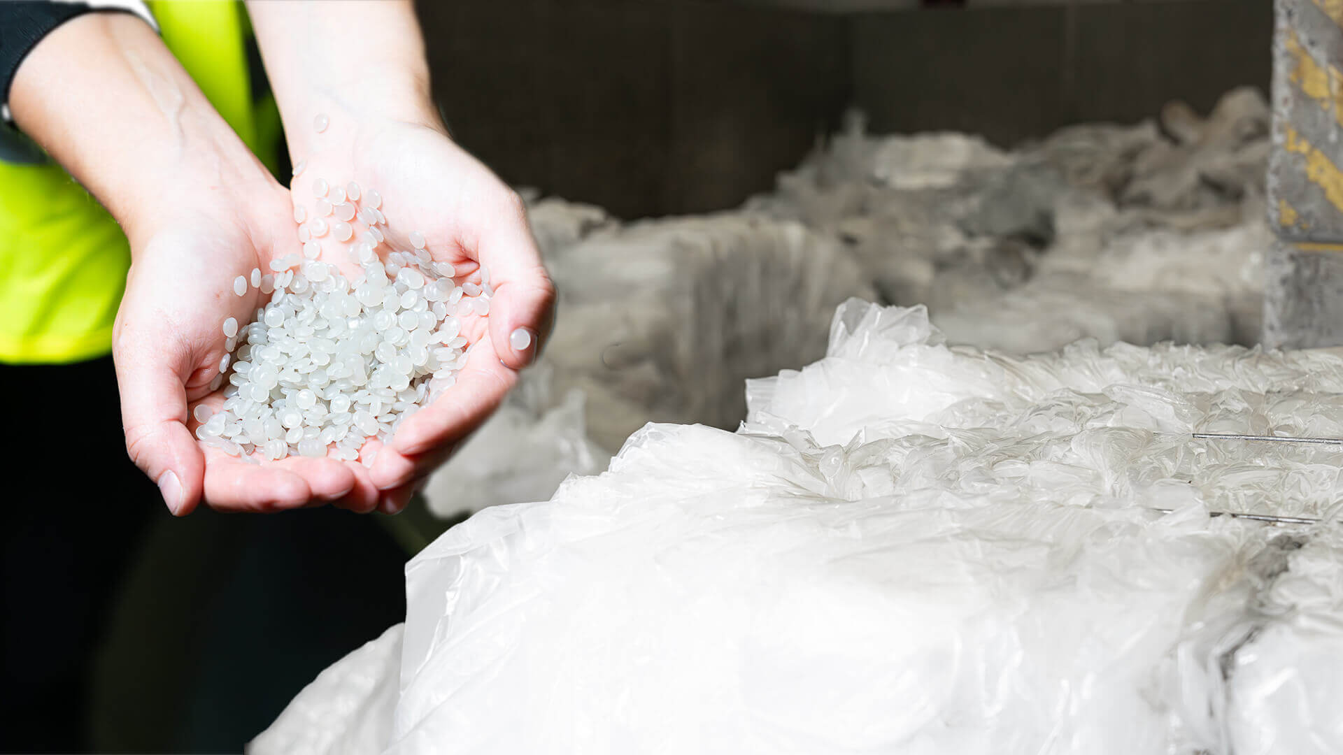 Hands filled with LDPE regranulate, next to it LDPE film in bales