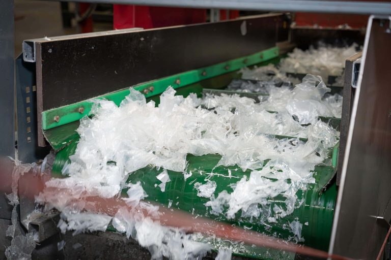 The shredded film remnants are transported onwards using a conveyor belt