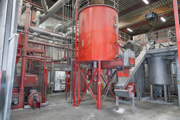 A large red mixing silo in an industrial hall