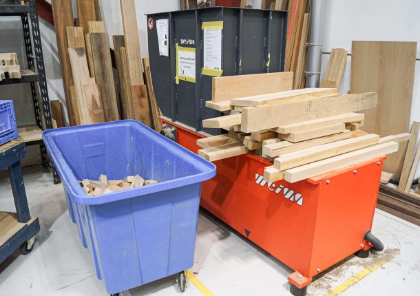 A red-orange Shredder with a blue box of wood waste and input material