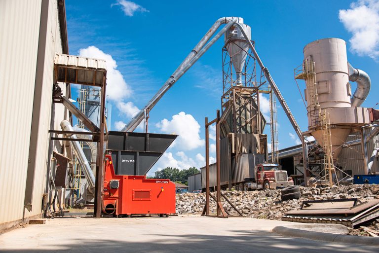 Orange WEIMA shredder outdoor with blue sky in front of production halls