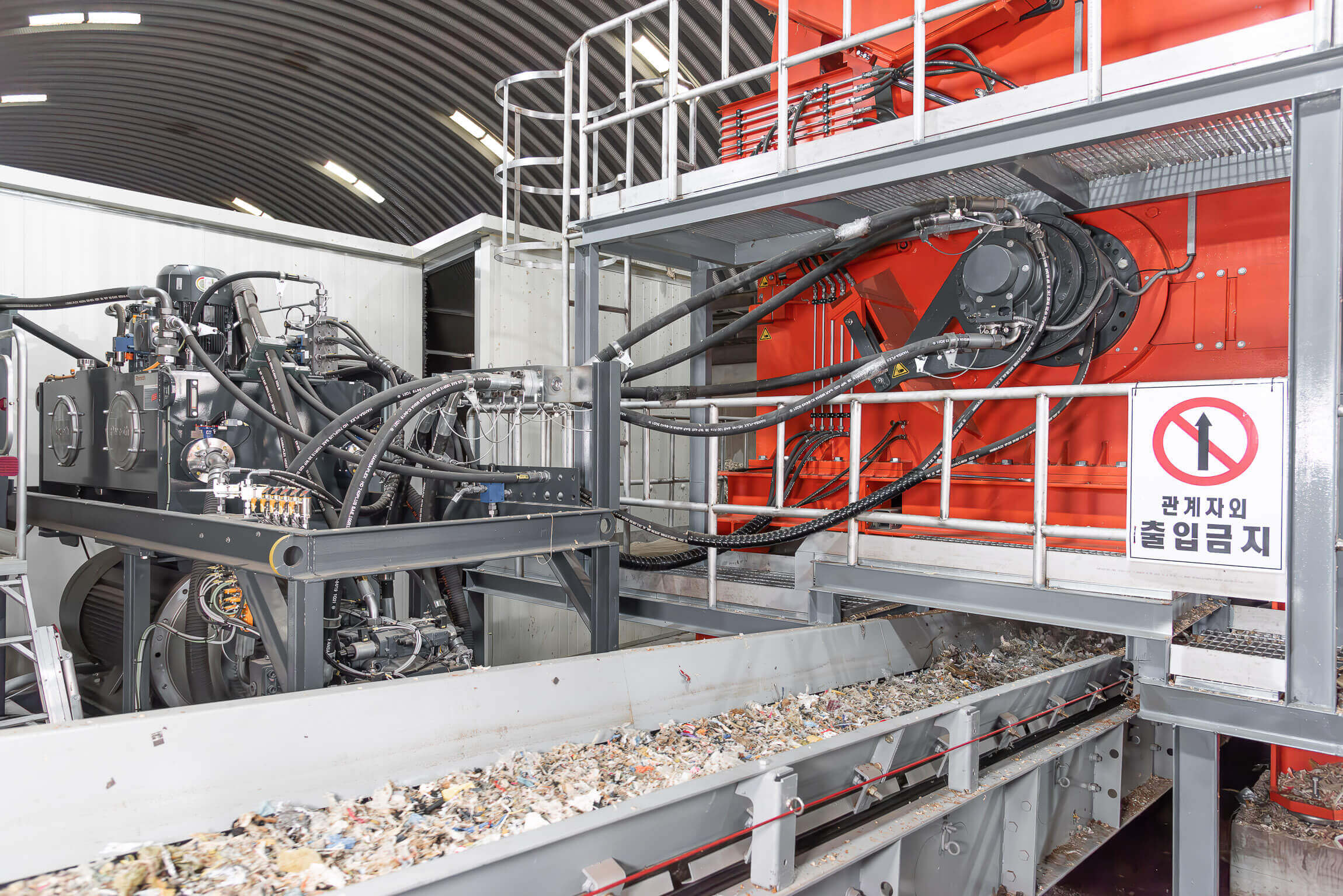 Austragsförderband mit zerkleinerten Müll, darüber ein Hydraulikantrieb von Hägglunds