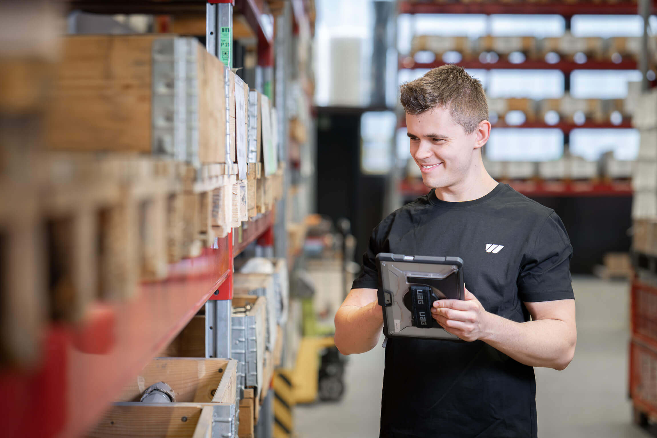WEIMA Mitarbeiter mit Tablet steht vor einem Hochregallager