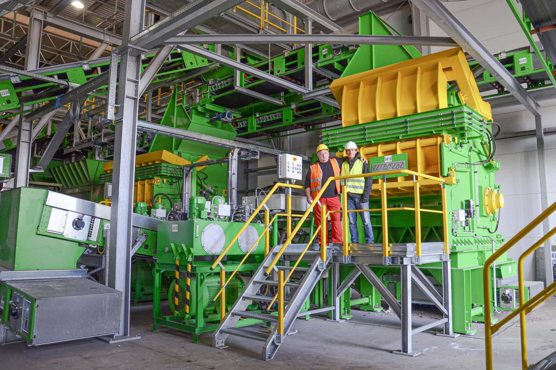 Green and yellow WEIMA shredders with conveyors, two persons standing in front of them