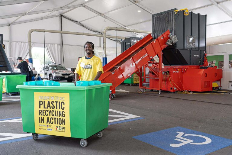 Destroy Responsibly program by WEIMA America at the NPE2024 trade show with WEIMA shredder, in front of it a person with a yellow shirt behind a green container