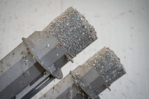 Dewatered and compressed gray lumps of plastic fines on the discharge pipes of a WEIMA C.200 Duo