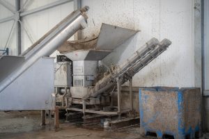 A silver stainless steel drainage press for dewatering plastic fines in an industrial hall