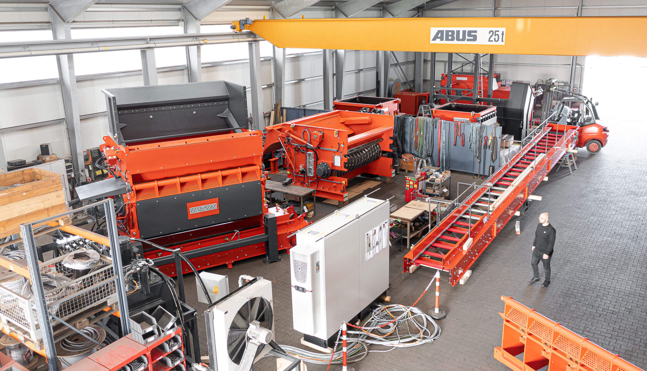 Mehrere orangefarbene WEIMA Shredder stehen nebeneinander in einem Produktionshalle von WEIMA