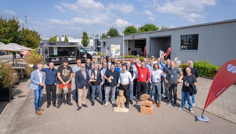 Eine Gruppe an lachenden Männern vor einem Firmengebäude.