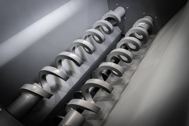 Two gray spirals in a hopper of a briquetting press