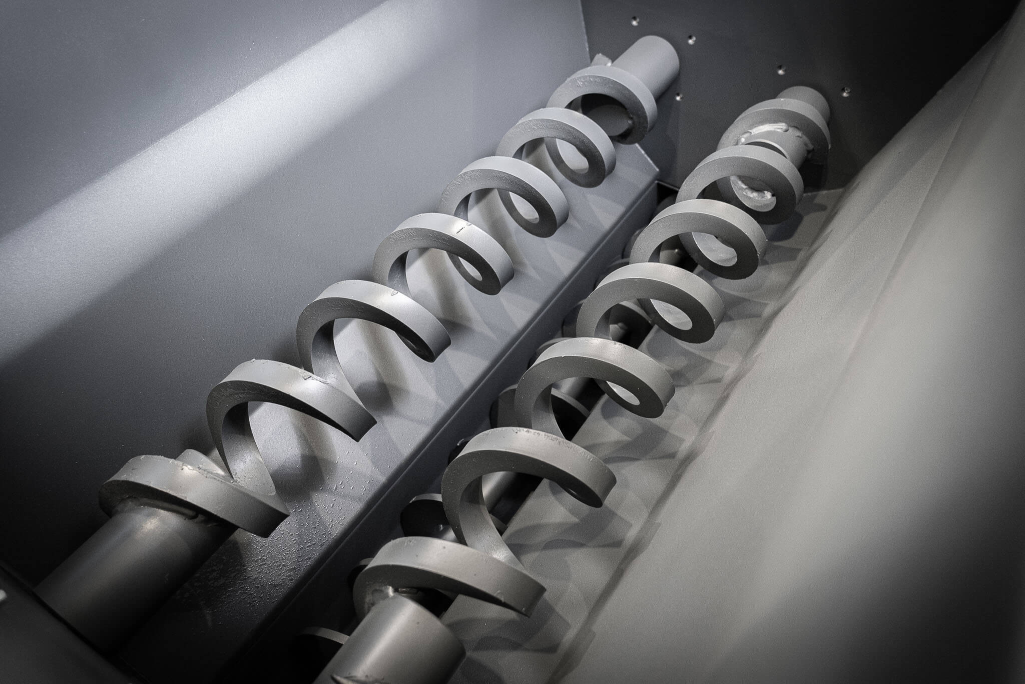 Two gray spirals in a hopper of a briquetting press