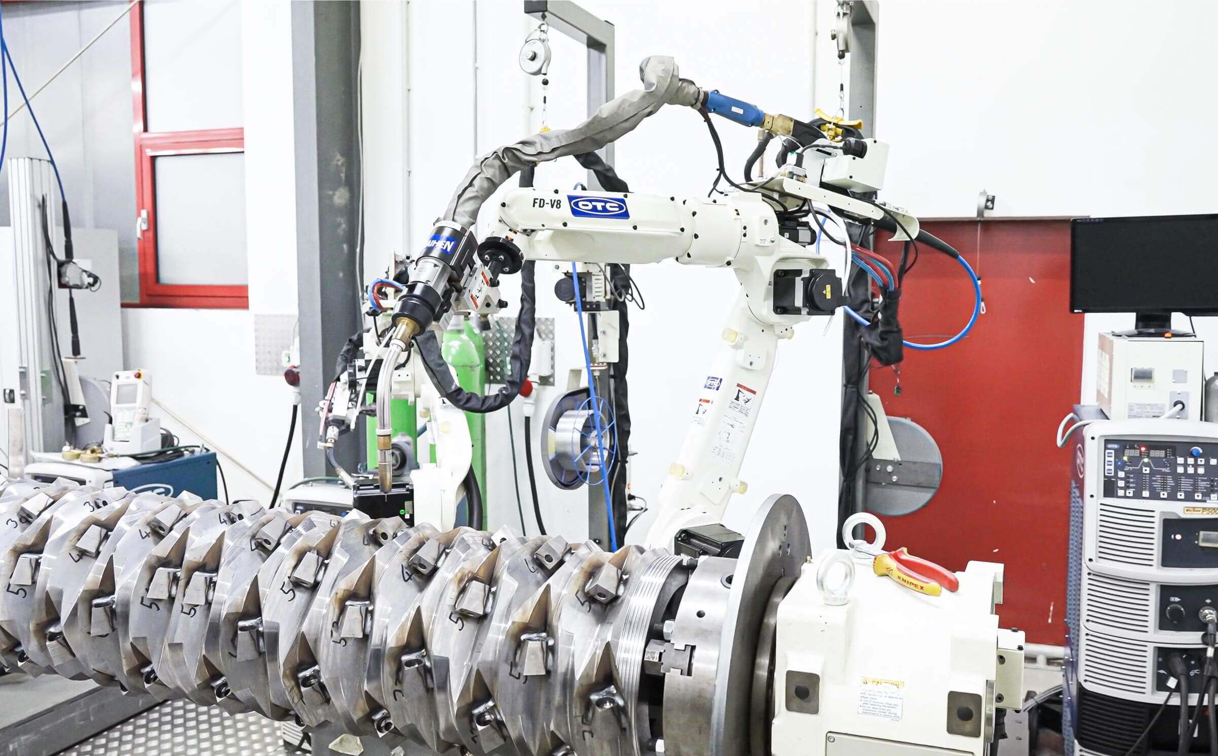 A white robot welding knives on a shredder rotor