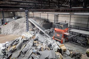 Top view of a WEIMA shredder with conveyor belt. Material for shredding is in the area in front of the shredder, the shredded material comes after the conveyor belt