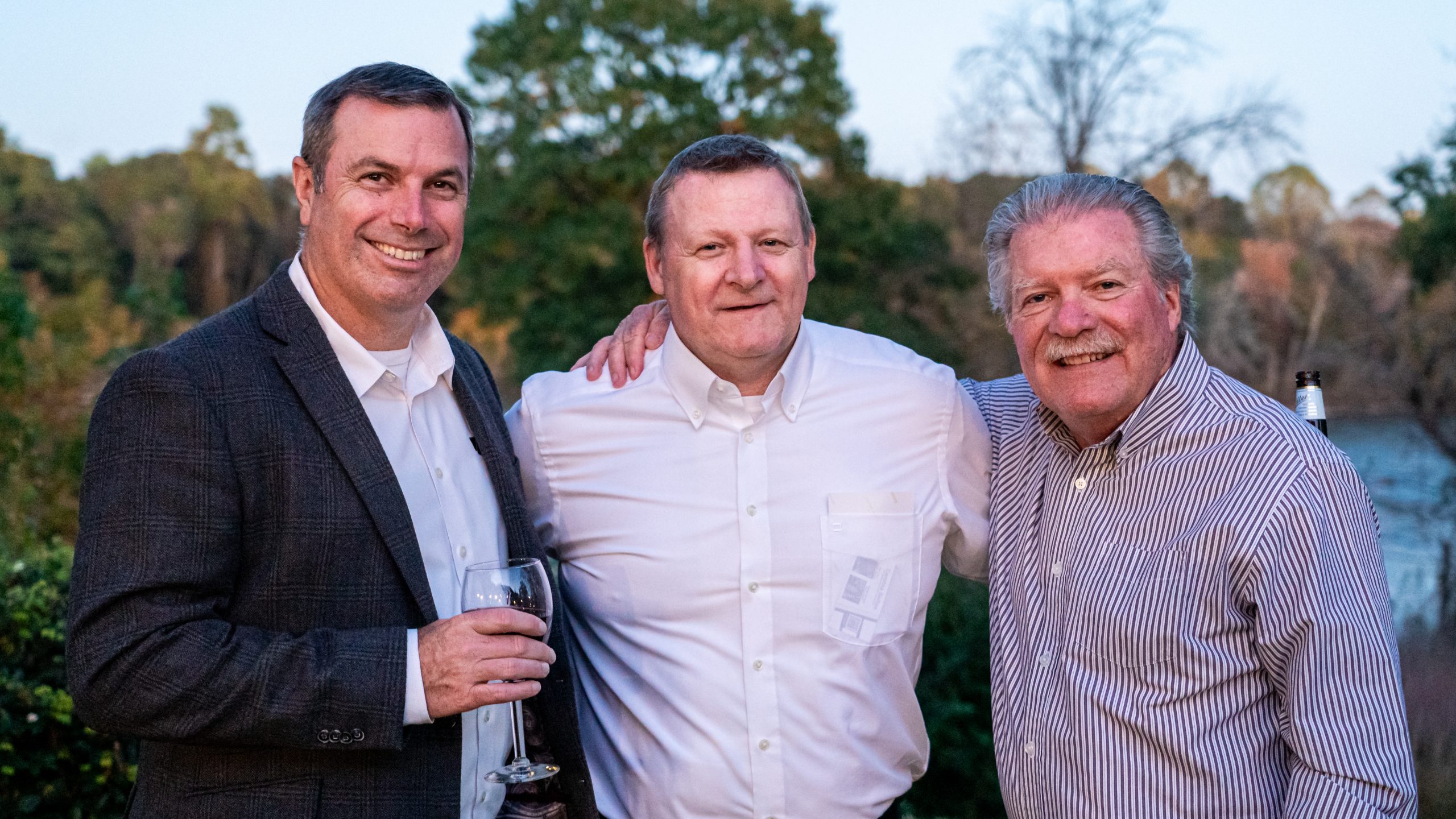 Drei Männer lächeln in die Kamera und posieren für ein Foto