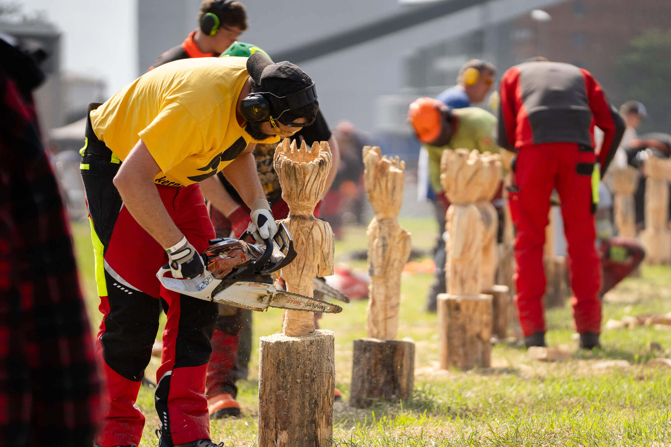 Mehrere Menschen sägen Skulpturen aus Holz