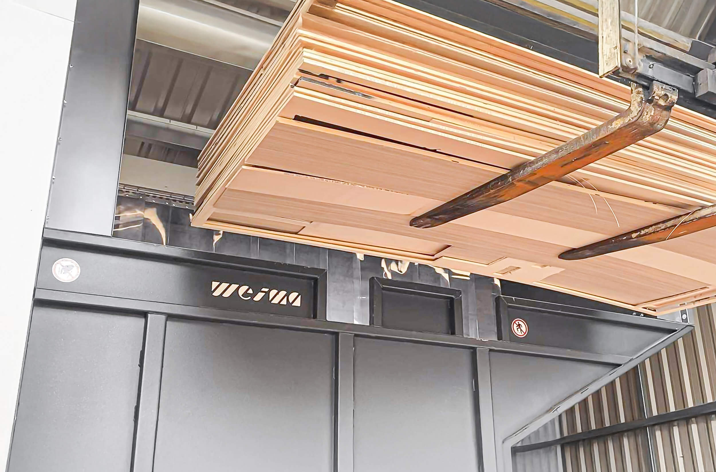 A forklift truck transports various wood scraps into a shredder