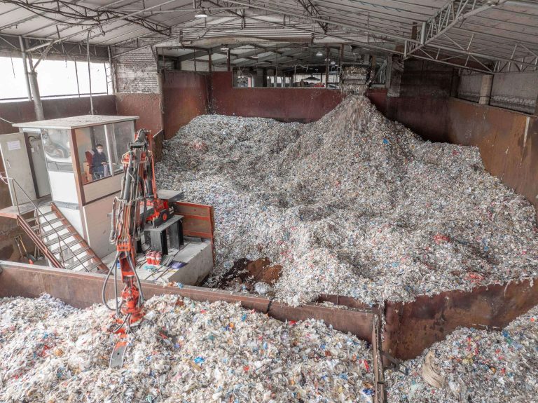 Blick von oben in den Bunker mit zerkleinertem Material, ein Kran transportiert das Material weiter.