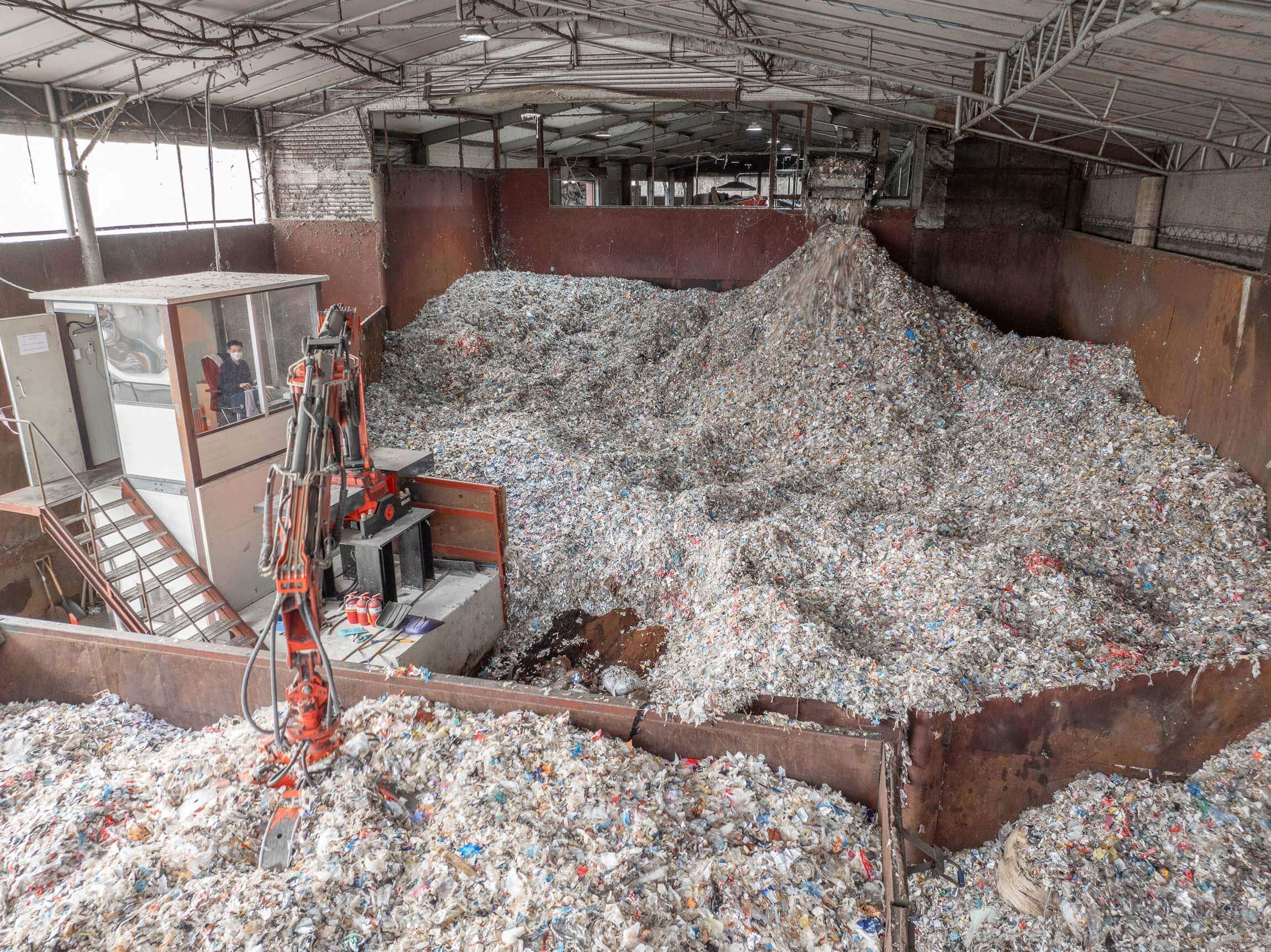 Blick von oben in den Bunker mit zerkleinertem Material, ein Kran transportiert das Material weiter.
