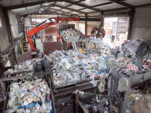 Blick auf den vielen Müll, der mit Förderbändern und Kran in den Shredder transportiert wird