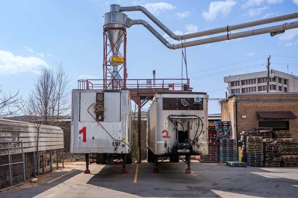 Two silver and white trailers sit side-by-side beneath the air system.