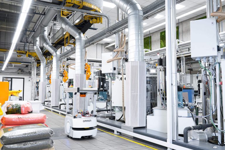 A white robot moves around the aisle next to pressing machines at Record Industry